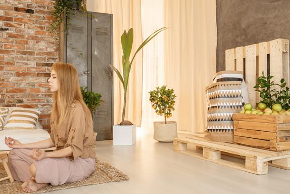 Meditating woman in her zen area in cozy wooden living room